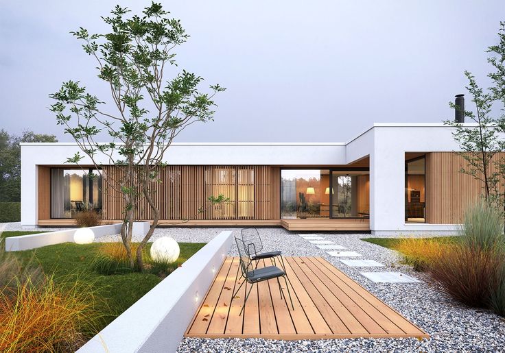 a modern house with wooden decking surrounded by grass and trees in the front yard