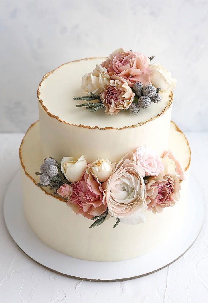 two tiered wedding cake with flowers on each layer and white frosting icing