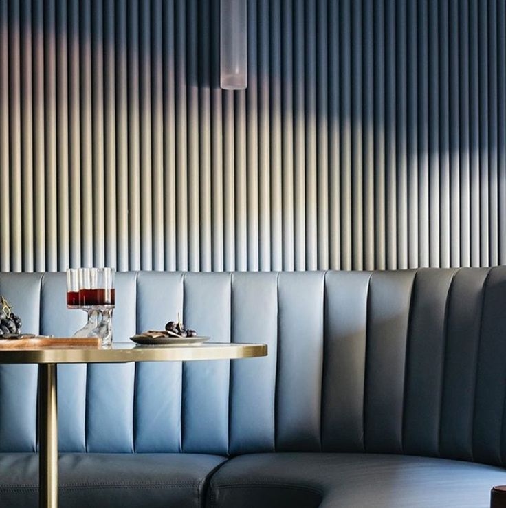 a table with two glasses on it in front of a wall made of vertical blinds