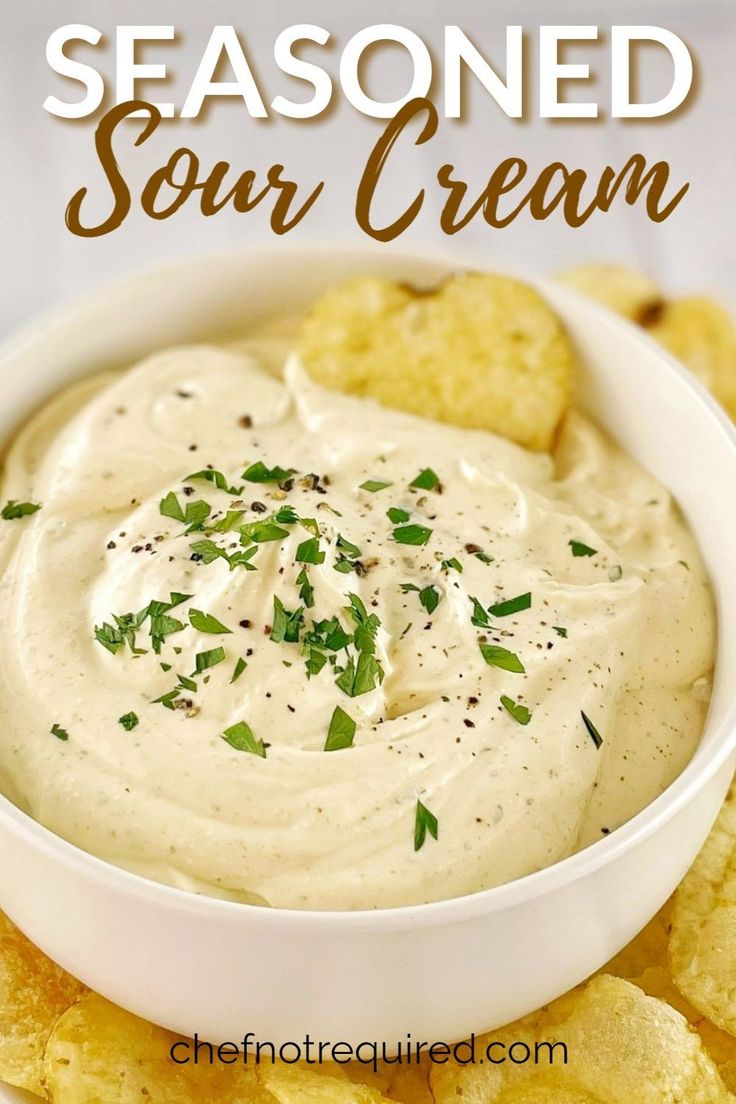 a white bowl filled with sour cream dip surrounded by crackers and parsley on the side