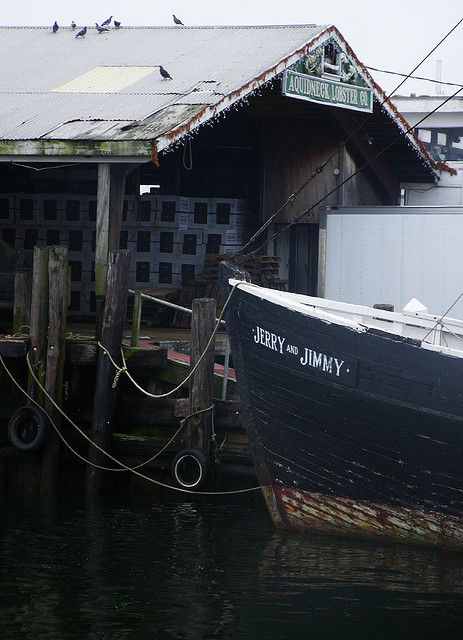 an old boat is tied up to the dock in front of a building with a sign on it