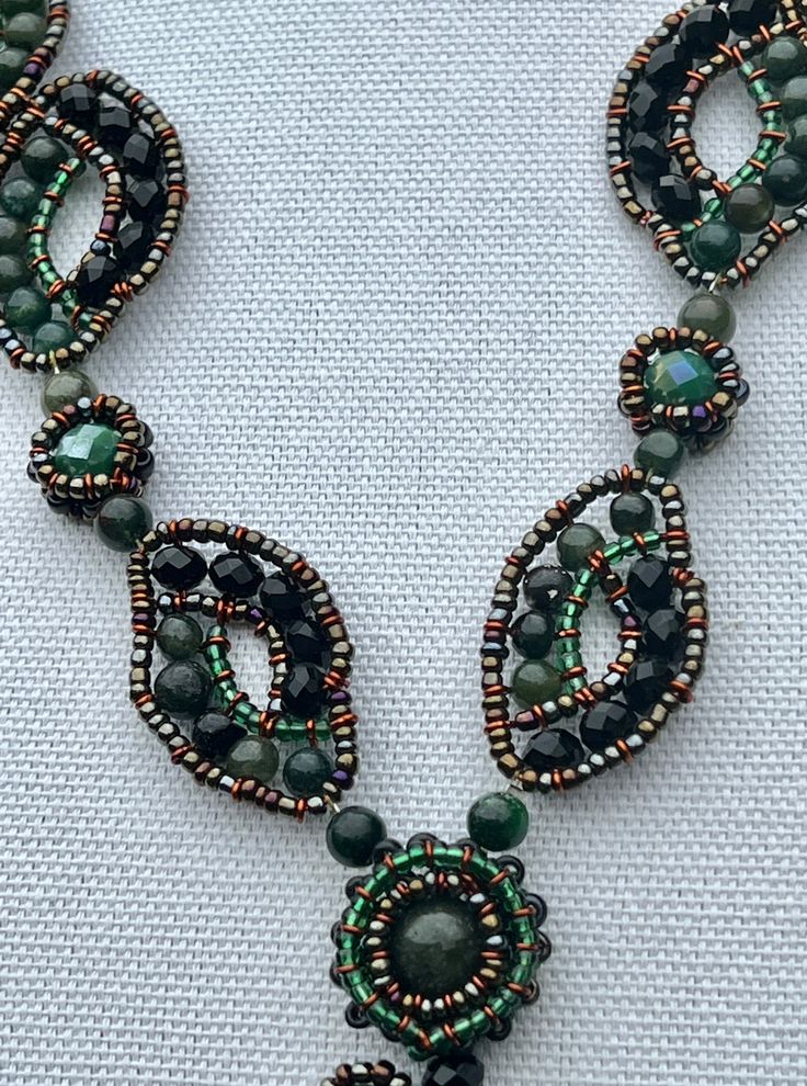 This necklace features jade beads woven into a stunning organic pattern. Seed beads are strategically incorporated to add interest and compliment the jade. This dramatic necklace would be a showcase for any outfit with its bold green color and design. It's from a husband and wife team that take beads, jade and present them in beautiful novel ways. It's handmade, and we procured the only one they had. Details: Button clasp. Size: Length of necklace: ~ 12" (30.5 cm); length of drop portion: ~ 3.5" Dramatic Necklace, Organic Pattern, Jade Beads, Green Gemstones, Husband And Wife, Bead Weaving, Green Color, Green Colors, Seed Beads