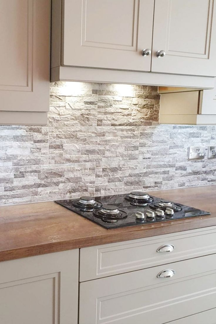 a stove top oven sitting inside of a kitchen next to wooden counter tops and white cabinets