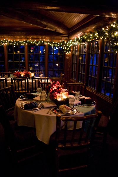 a dining room with lights strung over the windows and tables set for dinner in front of them