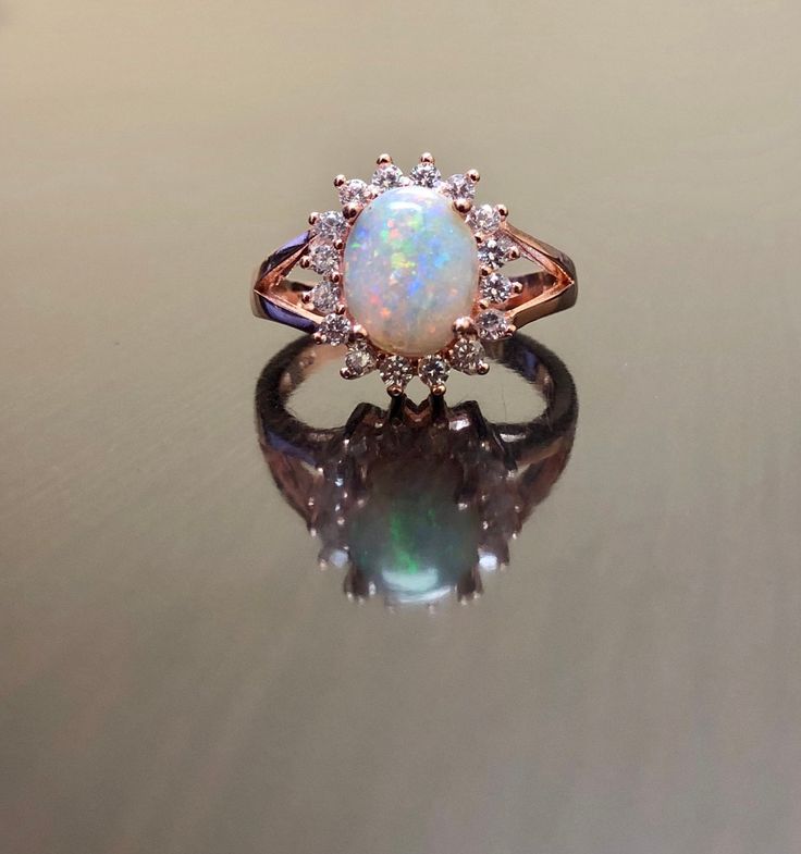 DeKara Designs Collection Our latest design! An elegant and lustrous Opal cabochon surrounded by beautiful diamonds in a halo setting. Metal- 14K Rose Gold, .583. Stones- Center Features an Oval Fiery Australian Opal Cabochon Cut 9 x 7 MM, 17 Round Diamonds, F-G Color VS1 Clarity, 0.32 Carats. Latest of my creations. A beautiful Opal Halo Diamond Ring. The Opal is professionally prong set in between four prongs. There are 17 professionally prong set round diamonds that are surrounding the opal. Exquisite Cabochon Wedding Ring, Luxury Rose Gold Opal Gemstone Ring, Fine Jewelry Wedding Opal Cabochon Ring, Wedding Opal Cabochon Ring In Fine Jewelry Style, Wedding Fine Jewelry Opal Cabochon Ring, Cabochon Opal Ring For Weddings, Wedding Cabochon Opal Ring, Elegant Rose Gold Opal Promise Ring, Luxury Rose Gold Cabochon Rings