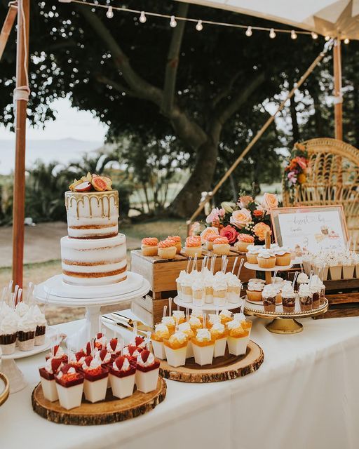 a table topped with cakes and cupcakes under a tent