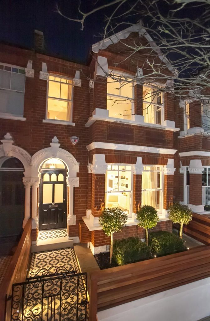 a large brick house with many windows and plants in the front yard at night time