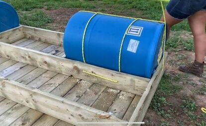 a blue barrel sitting in the back of a wooden crate on top of a field