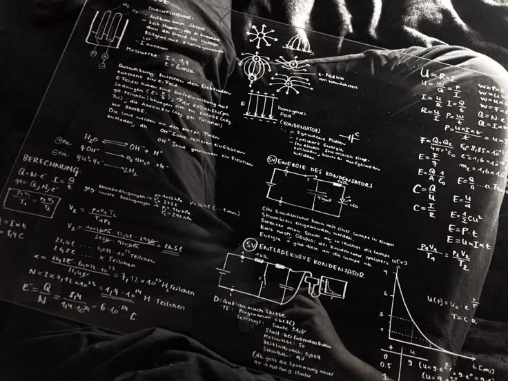 a person sitting in front of a blackboard with diagrams on it and writing on it