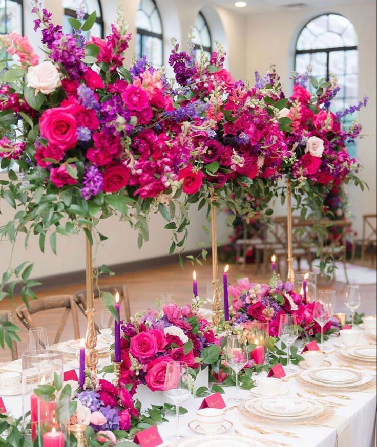 the table is set with candles, plates and flowers in vases on top of them