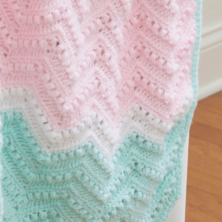 a crocheted blanket is laying on a chair