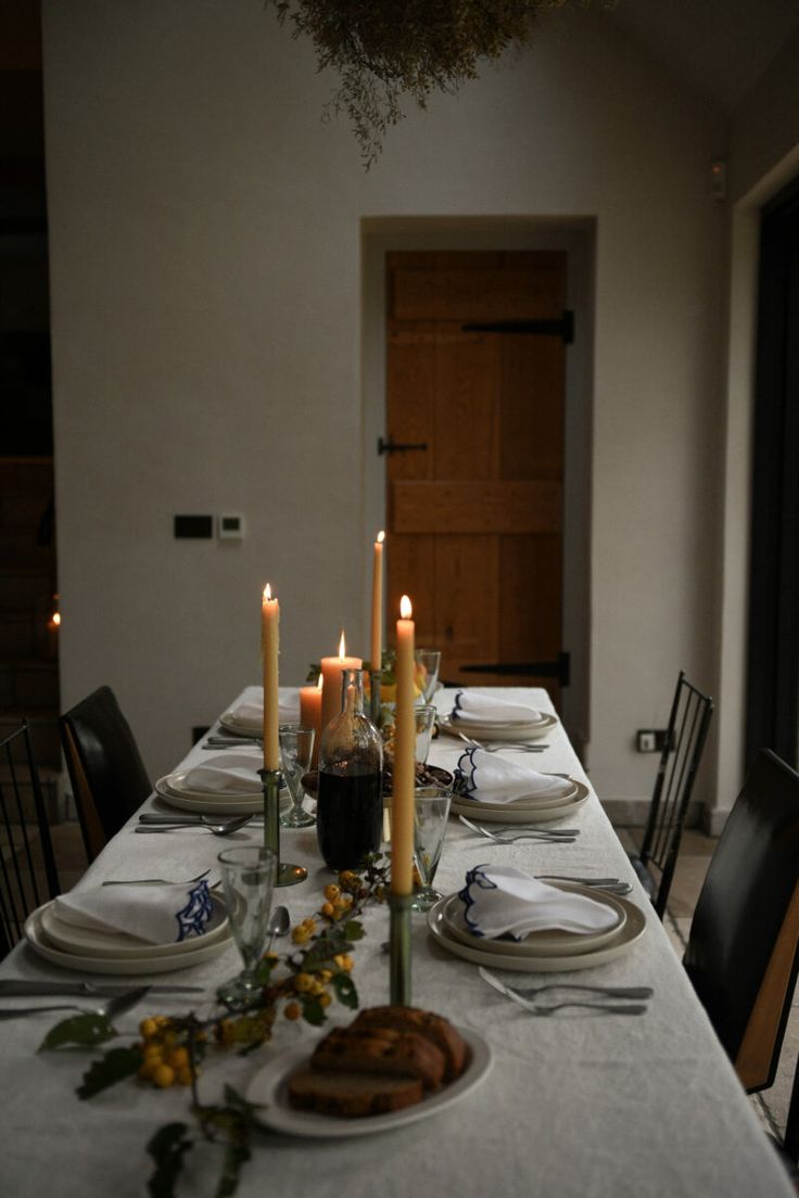 a table set with plates and candles for dinner