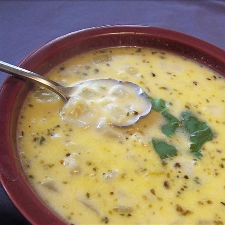 a red bowl filled with soup on top of a blue table cloth and a spoon