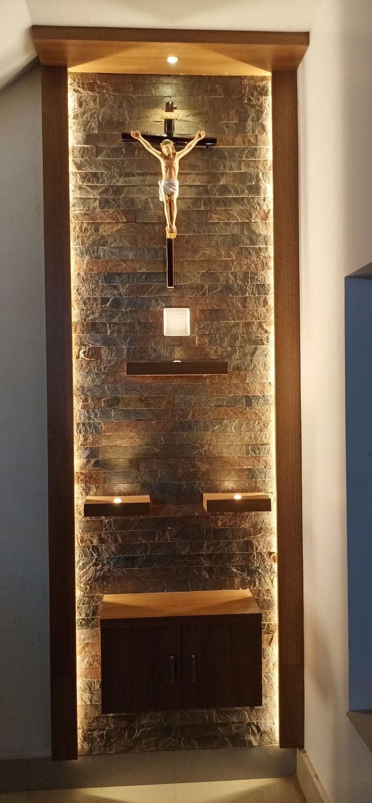 a crucifix in the corner of a room with stone walls and shelves