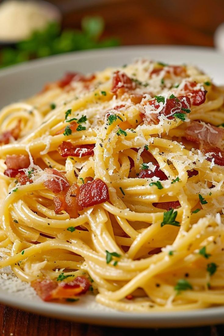 a plate of spaghetti with bacon and parmesan cheese