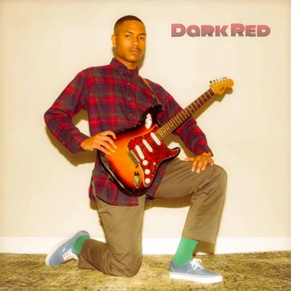 a man sitting on the ground with a guitar in his hand and wearing green socks