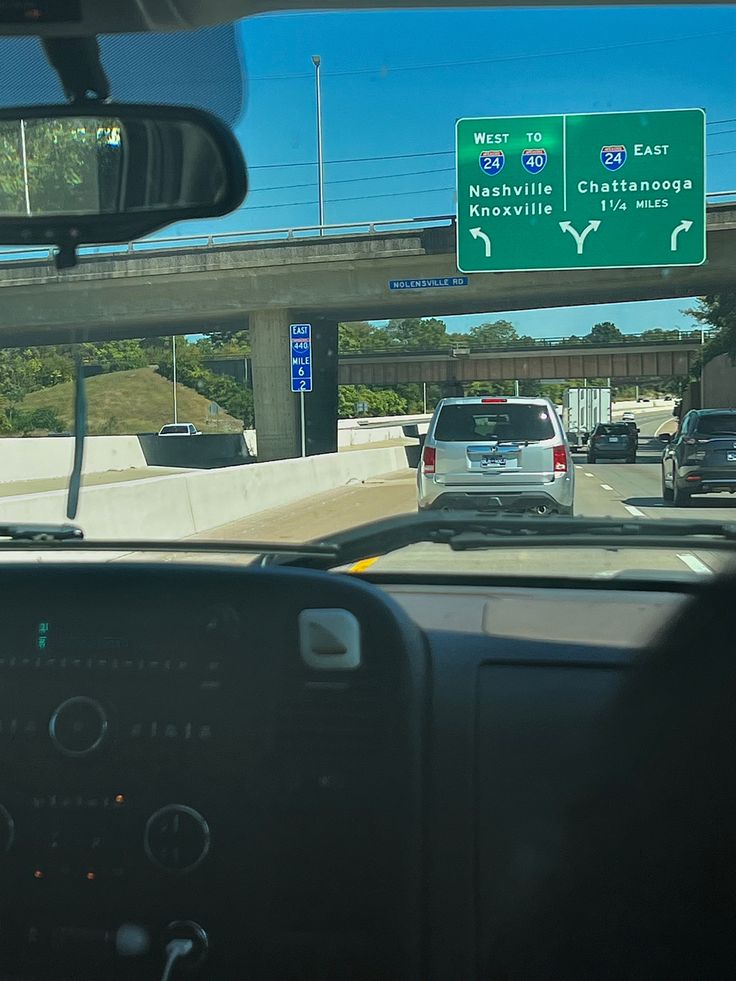 the view from inside a car looking at traffic and highway signs on an overpass