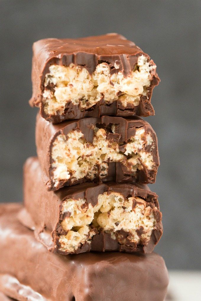 homemade crunch protein bars stacked on top of each other with chocolate and coconut in the middle