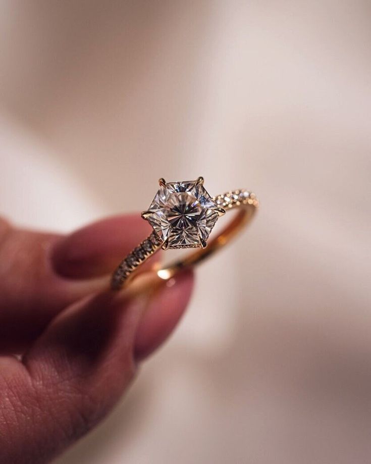 a hand holding a ring with a diamond in it's center, on a white background