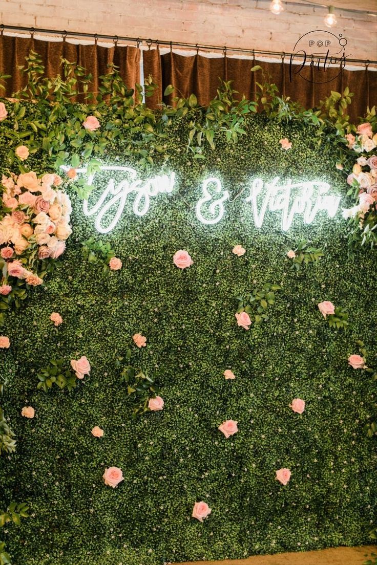 the wedding sign is surrounded by greenery and pink flowers on display at the reception