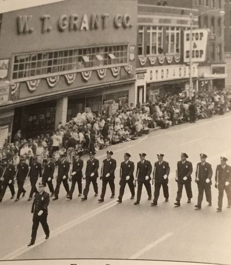 an old black and white photo of police marching down the street in front of a crowd