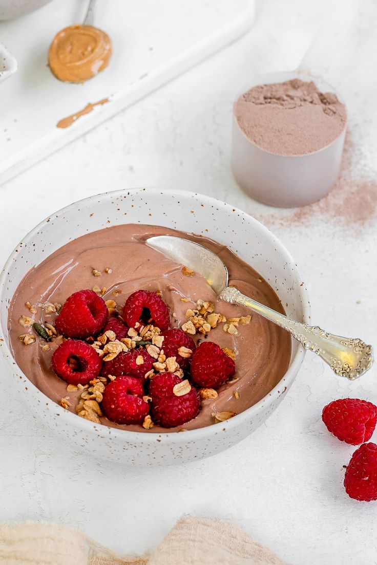 a bowl filled with chocolate and raspberries on top of a white countertop