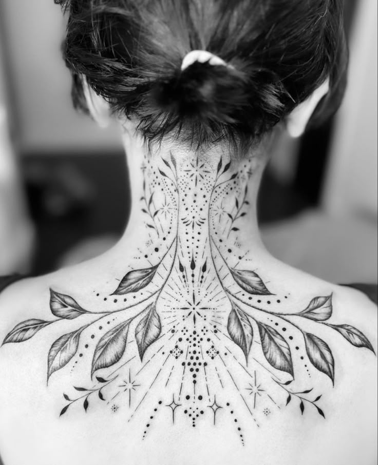 the back of a woman's neck with an intricate design on her upper back