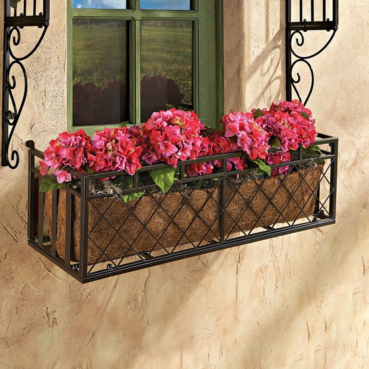 a window box filled with pink flowers next to a green door and window sill