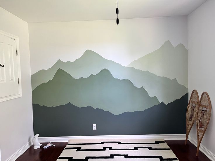 a living room with mountains painted on the wall and black and white area rugs