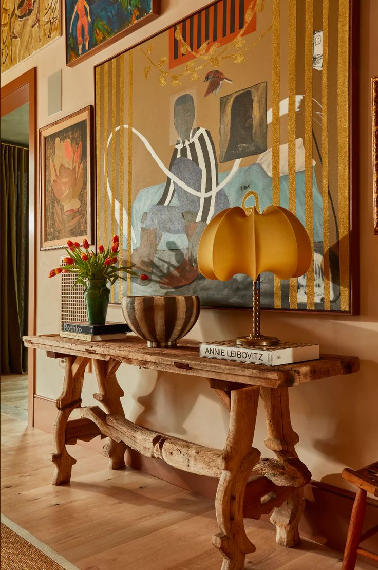 a wooden table sitting in front of a painting on the wall