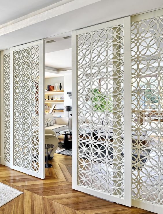 a living room with white walls and wooden floors in front of an open door to another room