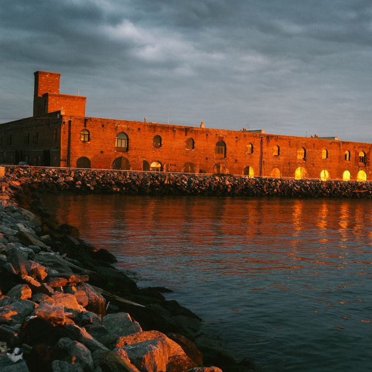 a large brick building sitting next to a body of water at night with lights on