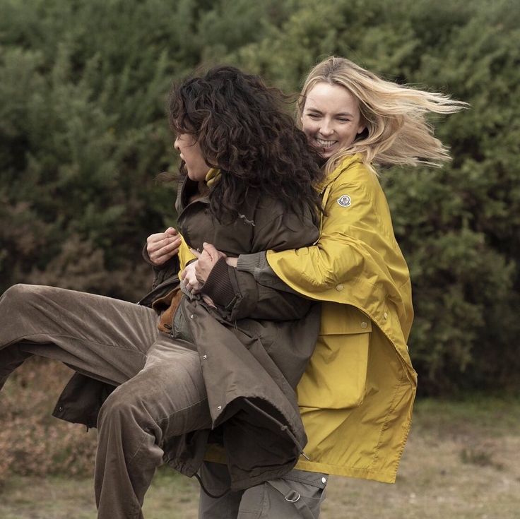 two young women are playing with each other in the grass and one is carrying another woman on her back