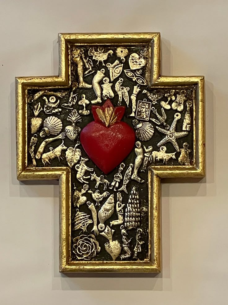 an ornate gold and black cross with a red heart on it's center piece