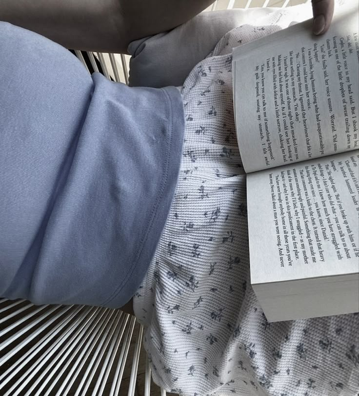 a person reading a book while sitting in a crib