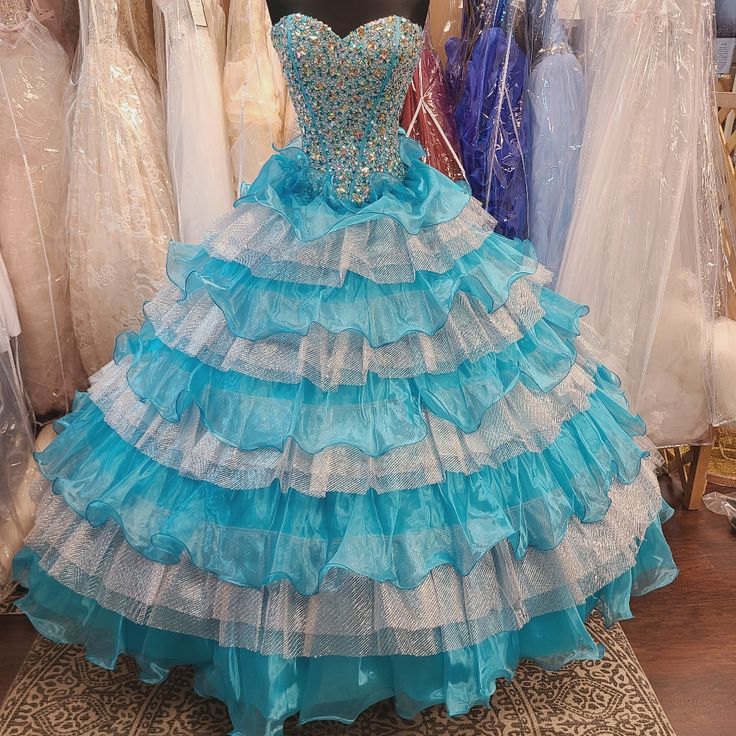 Blue Embellished Ball Gown With Fitted Bodice, Light Blue Fitted Ball Gown For Quinceanera, Fitted Light Blue Ball Gown For Quinceanera, Princess Style Blue Dress For Debutante Ball, Blue Princess Style Floor-length Gown, Blue Ruffled Dress For Debutante Ball, Embellished Blue Ball Gown For Prom, Blue Embellished Ball Gown For Prom Season, Blue Embellished Ball Gown For Prom