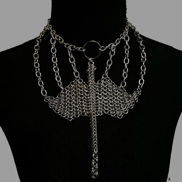 Unleash your inner dragon with the Dragon's Embrace Chainmail Necklace, a mesmerizing piece perfect for renaissance fairs and fantasy outfits. Crafted from silver anodized aluminum jump rings, this necklace features a stunning dragon intricately woven out of chainmail, showcasing exceptional artistry and detail. The Dragon's Embrace Chainmail Necklace is not just an accessory but a statement of strength, mystery, and timeless elegance. Let this unique piece adorn your neck, capturing the essence of mythical beauty and adding a touch of enchantment to your ensemble. Silver Gothic Jewelry For Fantasy Events, Gothic Metal Jewelry For Fantasy Events, Silver Gothic Necklaces For Fantasy Events, Silver Punk Necklace For Cosplay, Gothic Chain Body Jewelry For Festivals, Punk Silver Necklace For Cosplay, Medieval Style Silver Necklaces For Fantasy Events, Gothic Body Jewelry With Chain For Festivals, Gothic Festival Body Jewelry With Chain