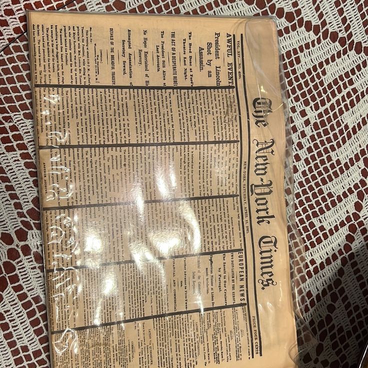 a newspaper laying on top of a red and white tablecloth covered in black writing