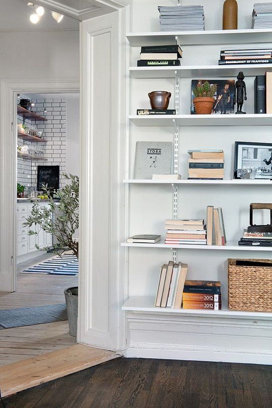 a white book shelf filled with books next to a doorway in a living room or dining room