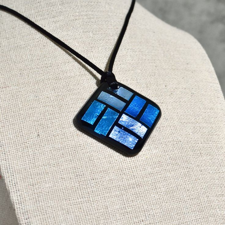 a necklace with blue squares on it sitting on a mannequin's torso