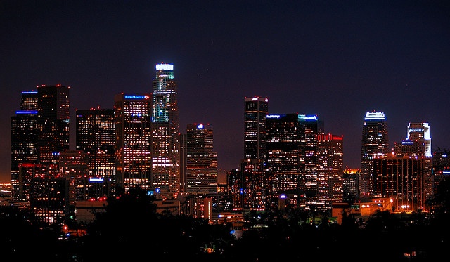 the city skyline is lit up at night with bright lights in the buildings and trees