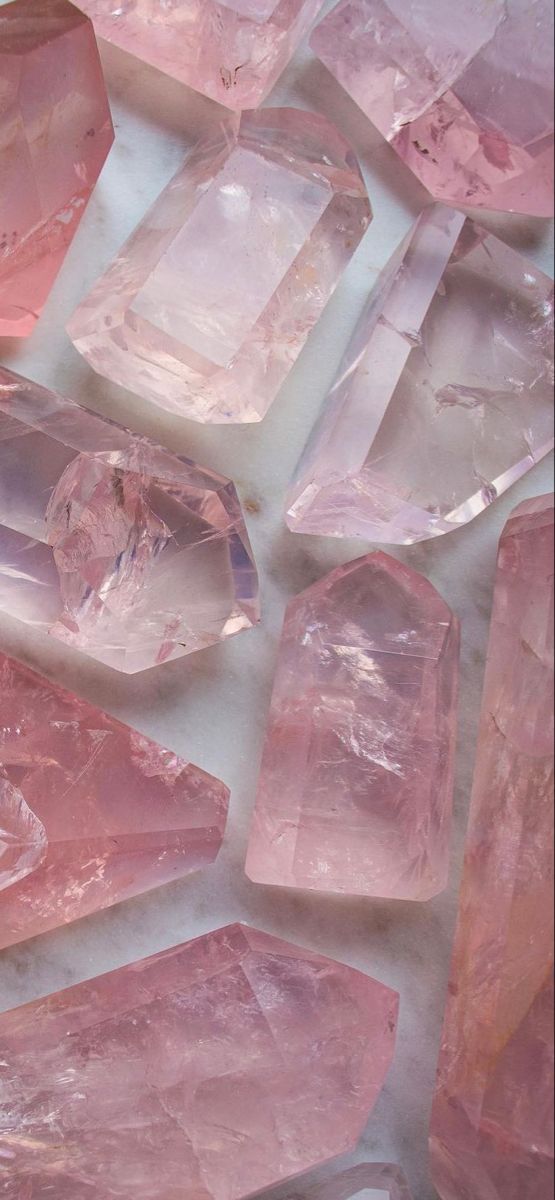 many pink crystals are arranged on a white surface