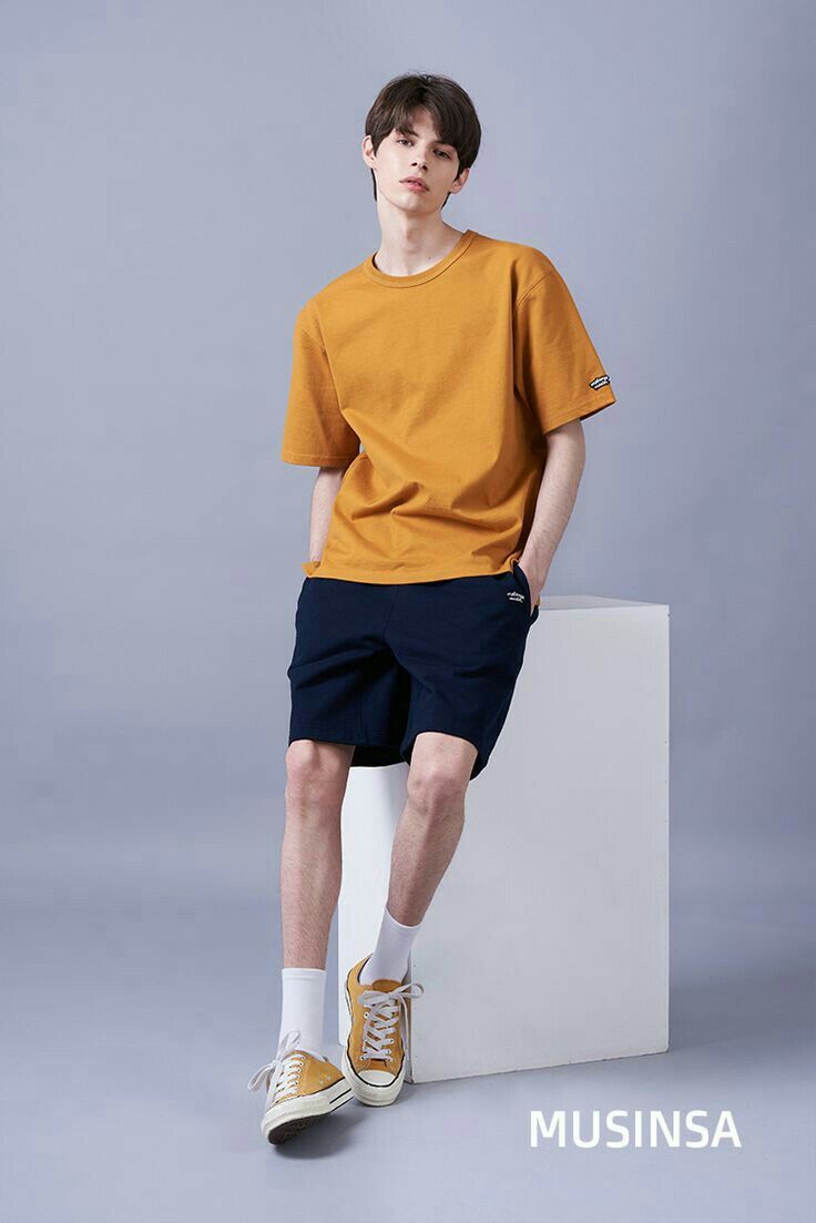 a young man sitting on top of a white box wearing shorts and a t - shirt