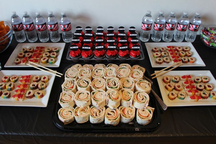 a table topped with plates and trays filled with food