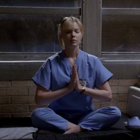 a woman in scrubs is meditating on the floor