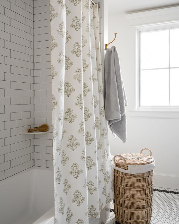 a bathroom with a shower curtain, rug and basket on the floor in front of it