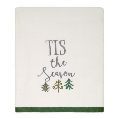 a white dish towel with the words tis the season on it and pine trees in green