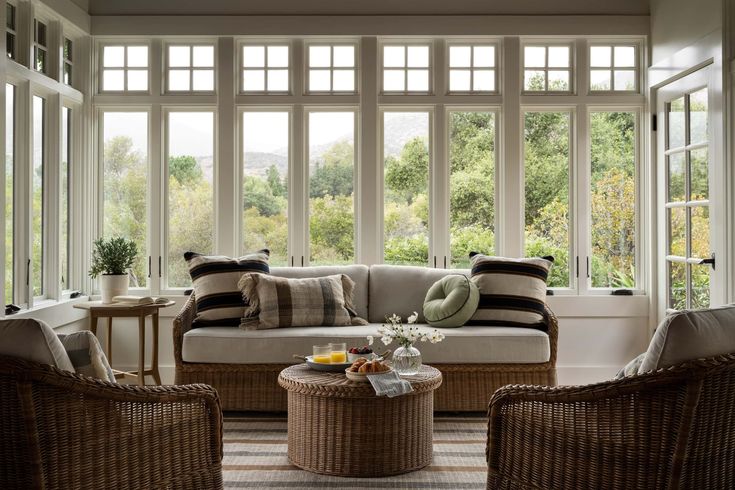 a living room with wicker furniture and large windows