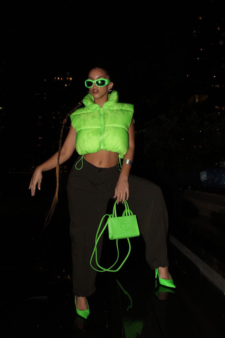 Neon puffer vest, olive green slacks, neon green pointed kitten heels, neon green mini Telfar purse, and neon green shades. Hairstyle: long, slicked braided ponytail. Black background Lime Green Black Outfit, Black Neon Outfit, Neon And Denim Outfits, Neon Green Boots Outfit, Lime Green Vest Outfit, Neon Green Heels Outfit, Neon Theme Party Outfit, Black And Neon Outfit, Neon Green Outfit Aesthetic