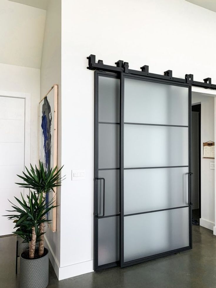 an open glass sliding door in a white room with potted plant next to it